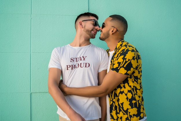 Foto casal gay abraçando e beijando na rua.