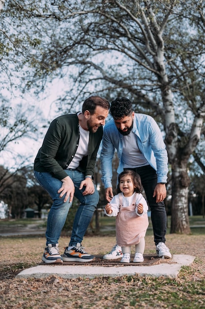 Casal gay com sua filha desfrutando de um dia em um parque dançando alegremente