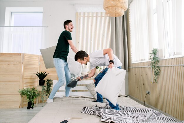 Casal gay lutando junto com almofadas na cama