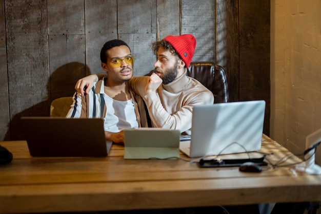 Casal gay trabalhando em computadores em home office