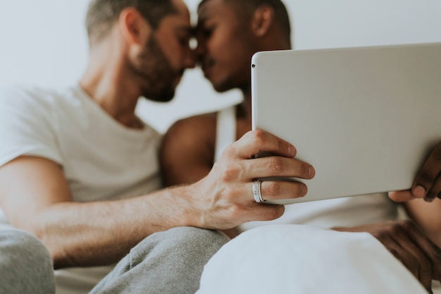 Casal gay usando um tablet na cama