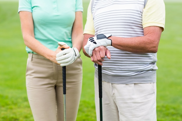 Casal golfista segurando clubes