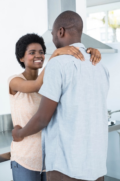 Casal grávida abraçando um ao outro na cozinha em casa