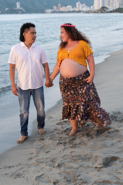 Casal grávida caminhando na praia