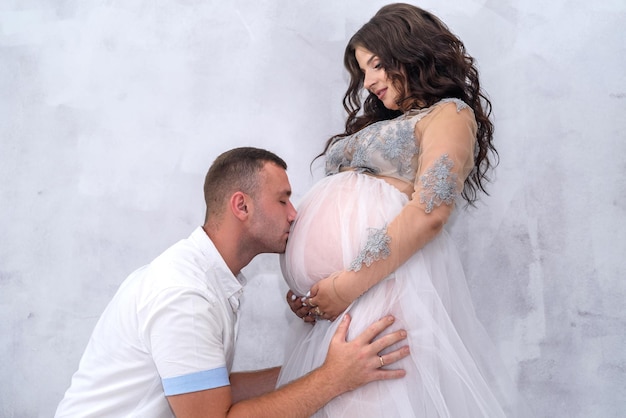 Casal grávida. Homem beijando sua linda esposa na barriga. Esperando por um bebê