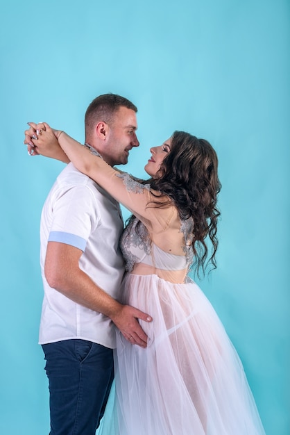 Casal grávida incrível posando em estúdio contra um fundo azul profundo, esperando por um bebê