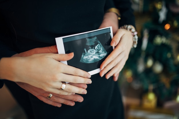 Casal grávida segurando a ultra-sonografia