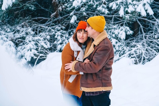 Casal homem e mulher abraçando em um fundo de floresta nevada