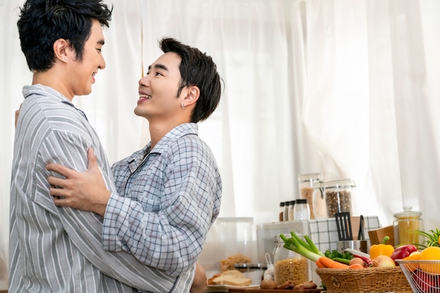 Casal homossexual asiático abraço e beijo na cozinha pela manhã. conceito lgbt gay.