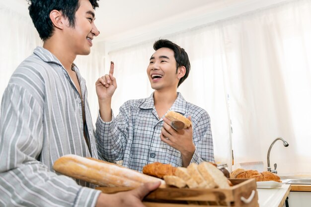 Casal homossexual asiático cozinhando o café da manhã na cozinha pela manhã. conceito lgbt gay.