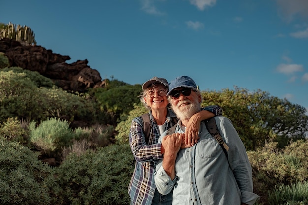 Casal idoso ativo sorridente desfrutando de excursão ao ar livre em ambiente montanhoso