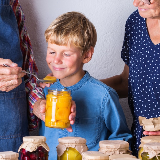 Casal idoso com neto degustando compota de frutas para preservação