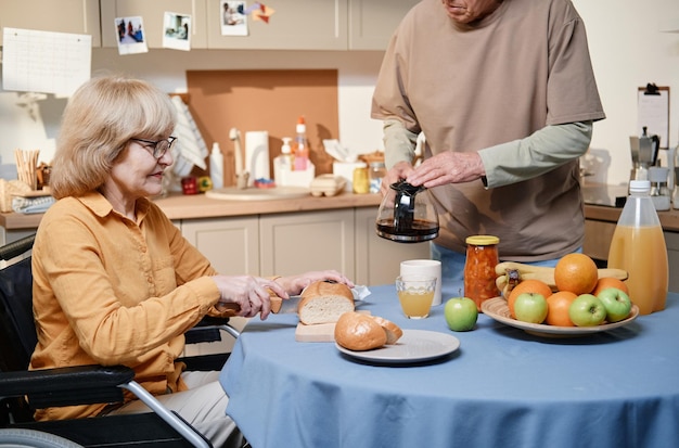 Casal idoso cozinhando o café da manhã juntos na mesa da cozinha