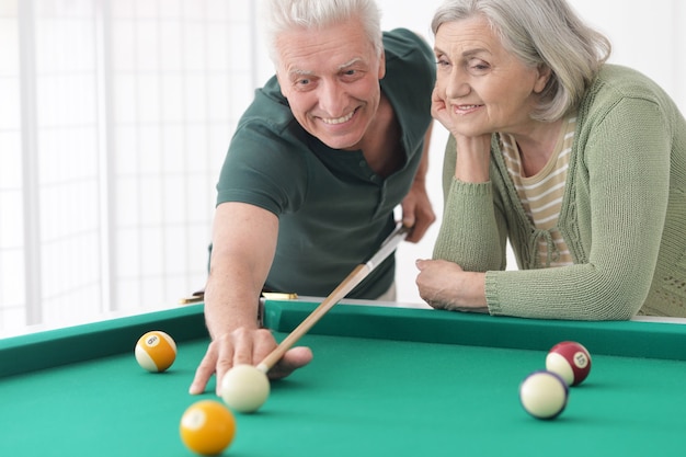 Casal idoso divertido de férias jogando bilhar