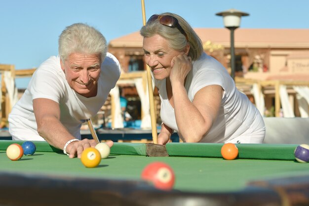 Casal idoso divertido de férias jogando bilhar