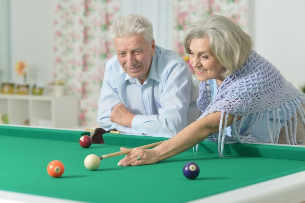 Casal idoso divertido de férias jogando bilhar