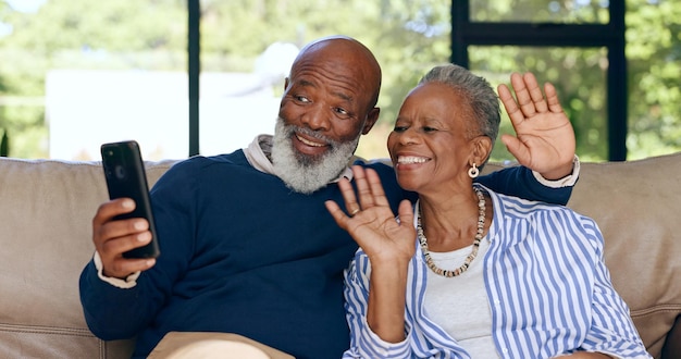 Foto casal idoso feliz chamada de vídeo e smartphone em casa para comunicação voip rede social ou conversar homem africano mulher e acenar olá para conversa virtual contato móvel ou falar na aposentadoria