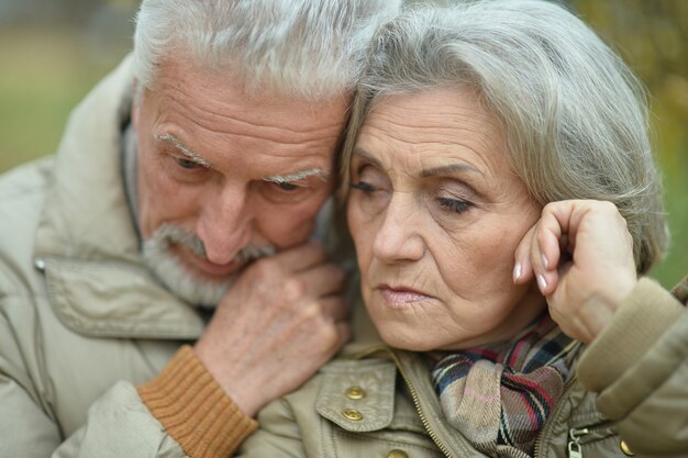 Casal idoso triste no parque outono perto