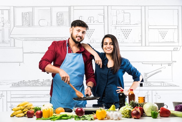 Casal indiano na cozinha - jovem linda esposa asiática gostando de cozinhar com o marido muitos vegetais frescos e frutas