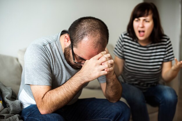 Casal infeliz discutindo no sofá