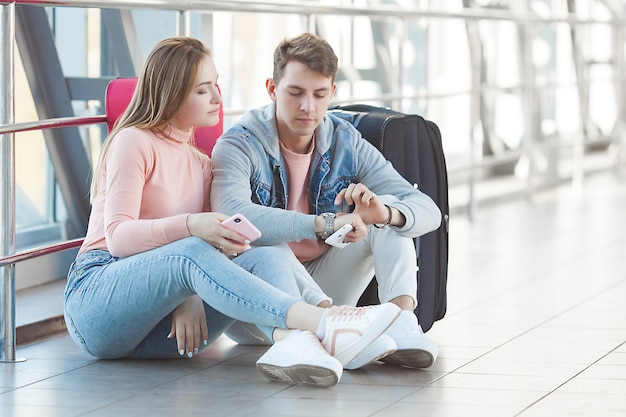 Casal infeliz esperando no aeroporto seu voo atrasado. Os jovens perderam o trem. Homem e mulher no aeroporto.