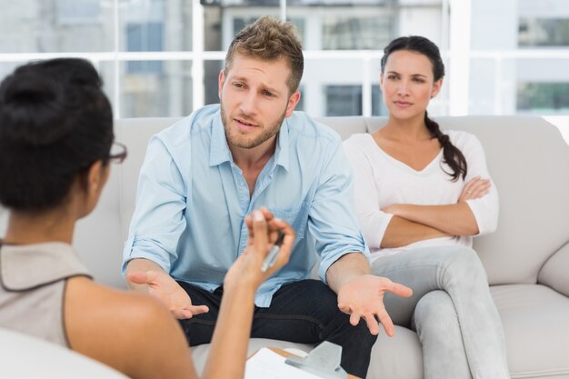 Casal infeliz na sessão de terapia com o homem falando com terapeuta