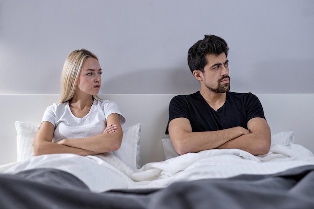 Casal infeliz não falando depois de uma discussão em casa. casal infeliz não falando depois de discutir. homem e mulher em luta com os braços cruzados, sentado na cama depois de brigar em casa.