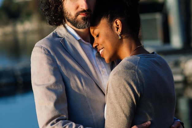 Foto casal interracial adulto jovem em uma praia, homem branco e mulher afro-americana em roupas casuais, aproveitando o dia de verão na costa do mar