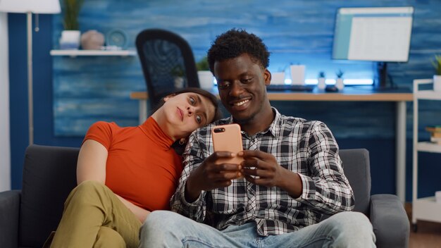 Casal interracial alegre tirando selfies com smartphone