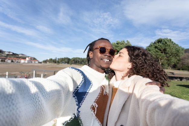 Casal interracial fazendo uma selfie enquanto beijava