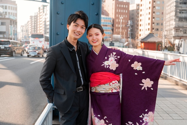 Foto casal japonês comemorando o dia da maioridade e posando juntos na cidade