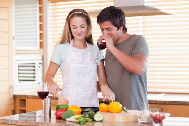 Casal jovem a cozinhar o jantar enquanto bebe vinho tinto