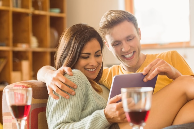 Casal jovem abraçando no sofá com tablet pc