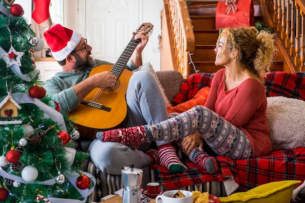 Casal jovem adulto feliz em casa, aproveita e celebra a véspera de Natal juntos, se divertindo e amando