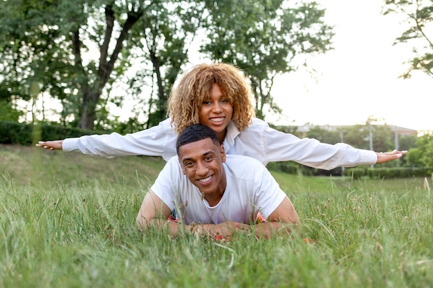 Casal jovem afro-americano apaixonado encontra-se juntos na grama do parque