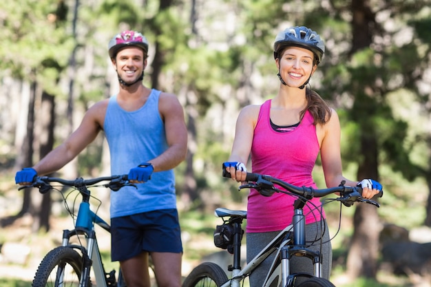 Casal jovem alegre com bicicletas de montanha