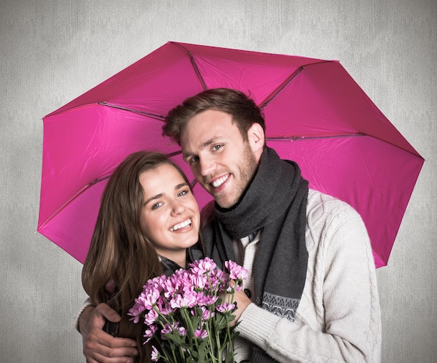 Casal jovem alegre com flores e guarda-chuva contra a superfície resistida