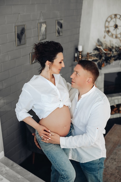 Casal jovem amoroso romântico, futuros pais esperando bebê. cara abraçando a esposa grávida com barriga nua no interior aconchegante de casa. foto de alta qualidade