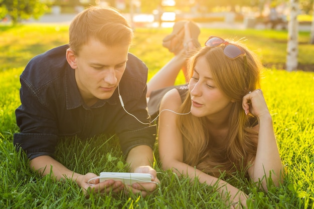 Casal jovem apaixonado no parque de verão ouvindo música.