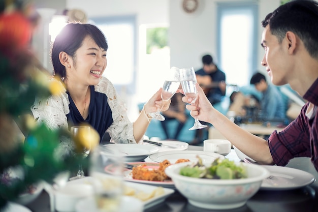 Casal jovem asiático, desfrutando de um jantar romântico à noite bebidas enquanto está sentado na mesa de jantar na