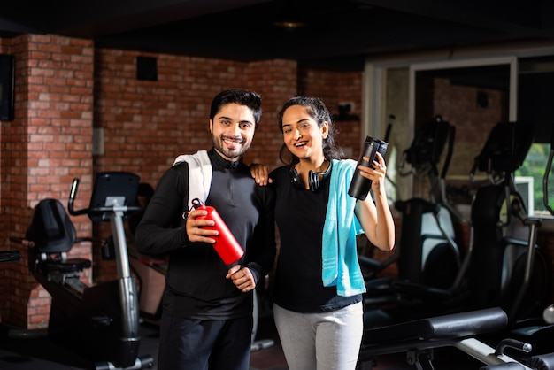 Casal jovem asiático indiano está malhando no ginásio. Mulher atraente e homem bonito e apto estão treinando em uma academia moderna - conceito de saúde e fitness