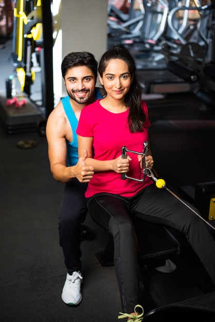 Casal jovem asiático indiano está malhando no ginásio. Mulher atraente e homem bonito e apto estão treinando em uma academia moderna - conceito de saúde e fitness