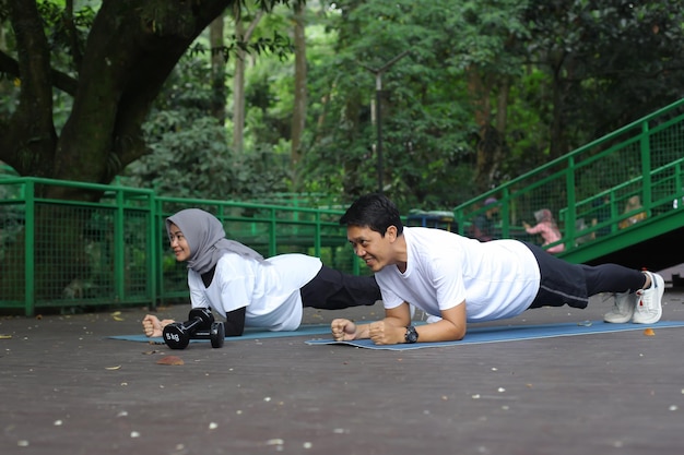 Casal jovem asiático saudável exercitando e fazendo prancha juntos no parque. Conceito de estilo de vida saudável