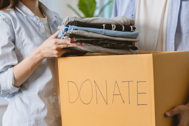 Foto casal jovem asiático voluntário feliz desembalar, embalar roupas, objeto de caridade em caixa de papelão, caixa dar segundo, reutilizado para doar. mulher, homem preparando realocação em movimento, nova casa, apartamento.