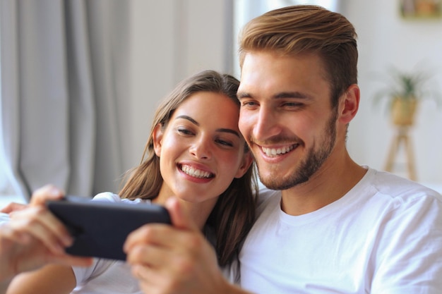 Casal jovem assistindo conteúdo online em um telefone inteligente, sentado em um sofá em casa na sala de estar