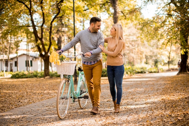 Casal jovem ativo desfrutando de um passeio romântico com bicicleta no parque outono dourado