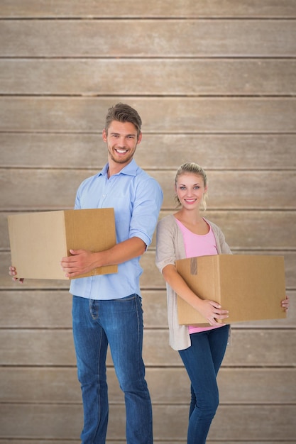 Casal jovem atraente carregando caixas em movimento contra pranchas de madeira