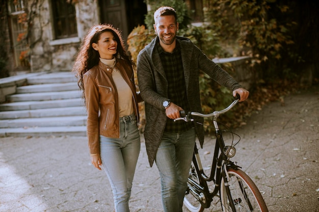 Casal jovem bonito andando de bicicleta no parque outono