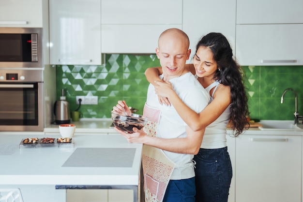 Casal jovem bonito eu falando, olhando e sorrindo enquanto cozinhava na cozinha.