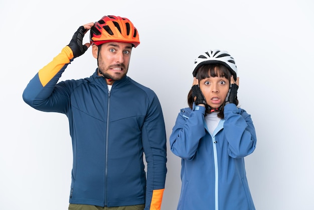 Casal jovem ciclista isolado em fundo branco leva as mãos na cabeça porque tem enxaqueca